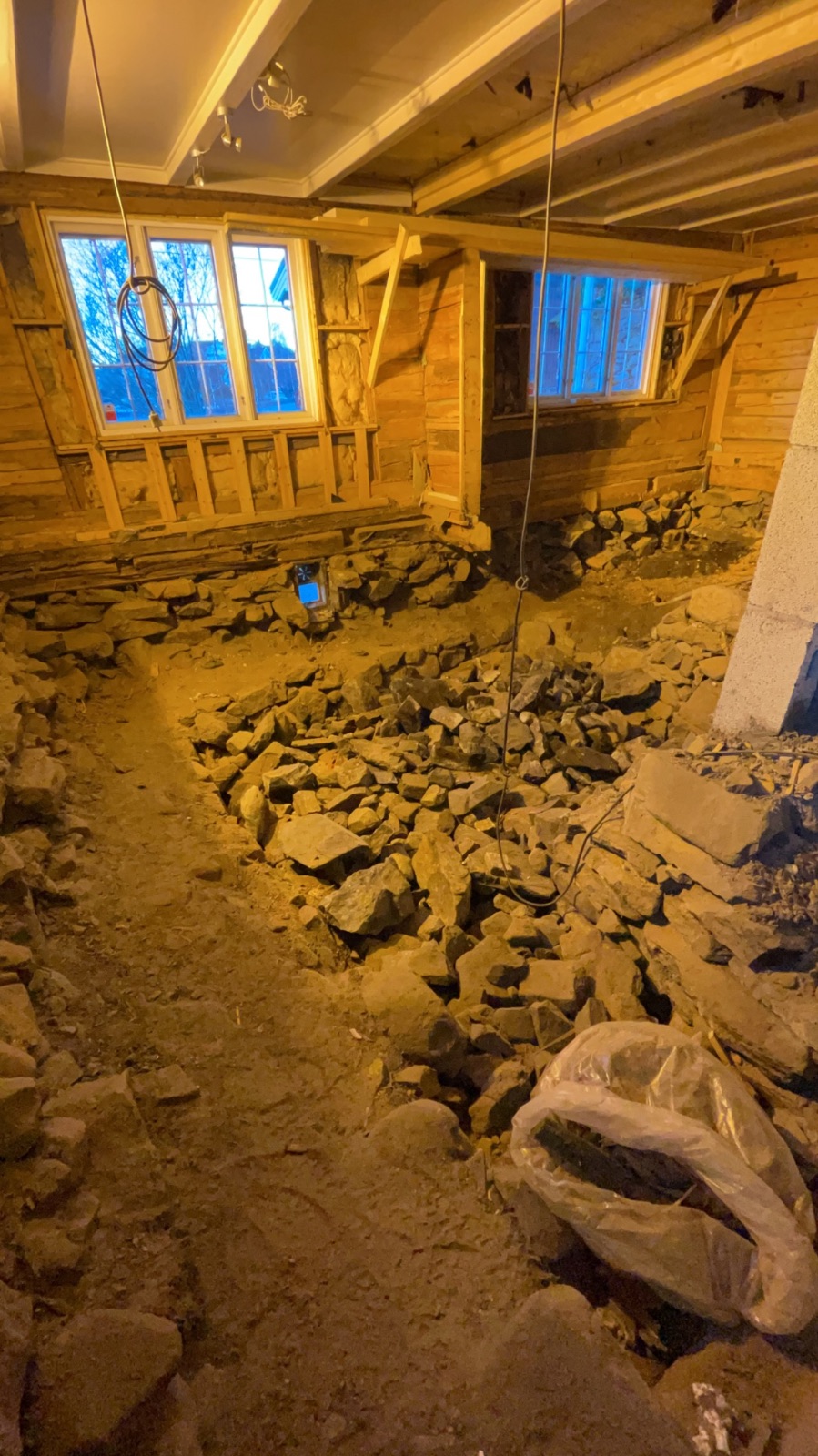 Krypkjelleren i trehuset åpnet: steinmasser og gammel grunnmur mellom tømmerveggene, med nye vinduer og avstivet reisverk